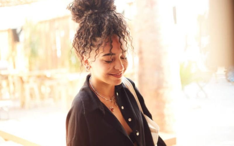 Black woman with a curly high ponytail hairstyle.