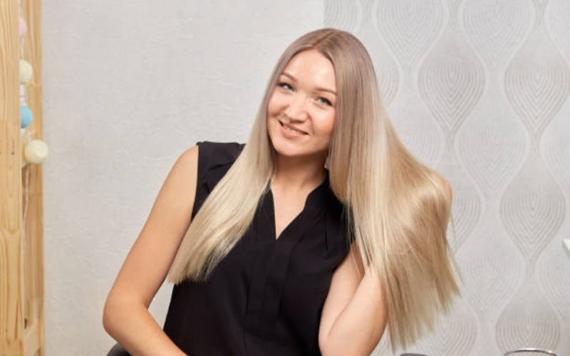Confident woman with shiny platinum blonde hair in natural light, showing a healthy and salon-quality final result.