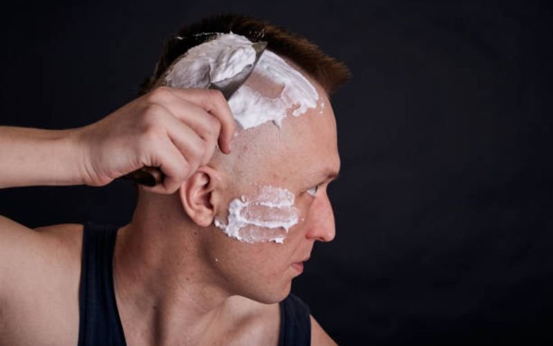 Applying shaving gel to scalp before shaving