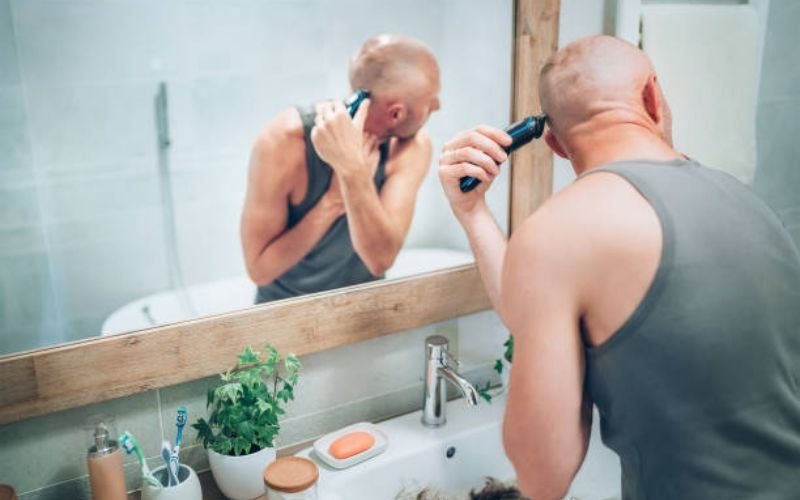 Man shaving his head carefully following proper steps for a safe shave.