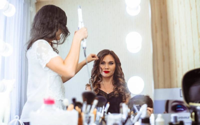 Hairstylist fixing a bride’s long hair during wedding day touch-up session