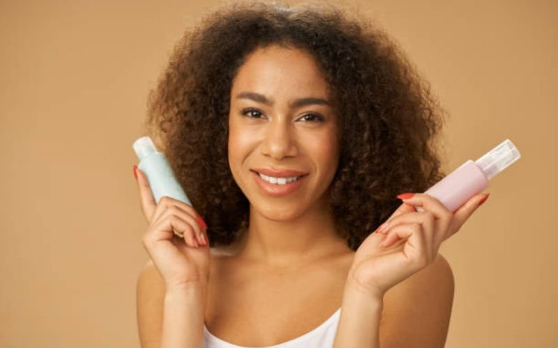 Woman with healthy melanin-rich curls holding hair products