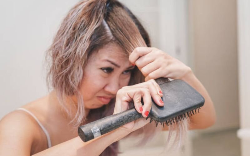 woman overwashing and aggressively brushing hair causing dryness